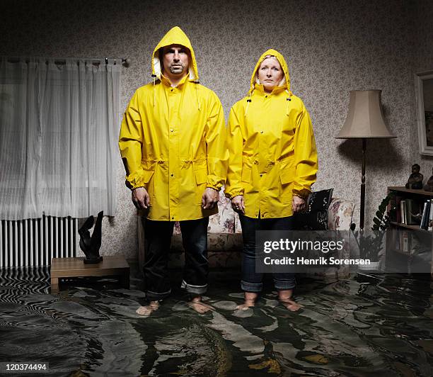 young pair in flooded room - gabardina ropa impermeable fotografías e imágenes de stock