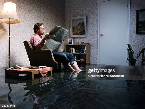 man with newspaper flooded room - ignorance foto e immagini stock