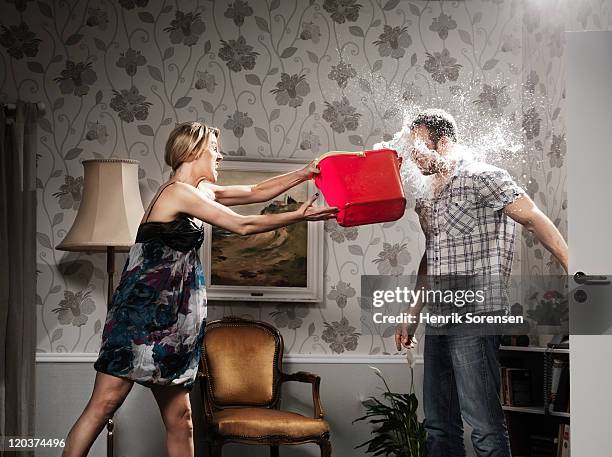 woman thowing a bucket of water at her partner - confrontation photos et images de collection