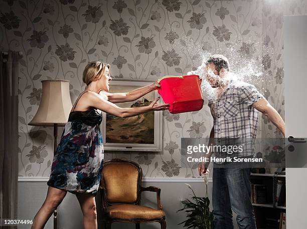 woman thowing a bucket of water at her partner - relatieproblemen stockfoto's en -beelden