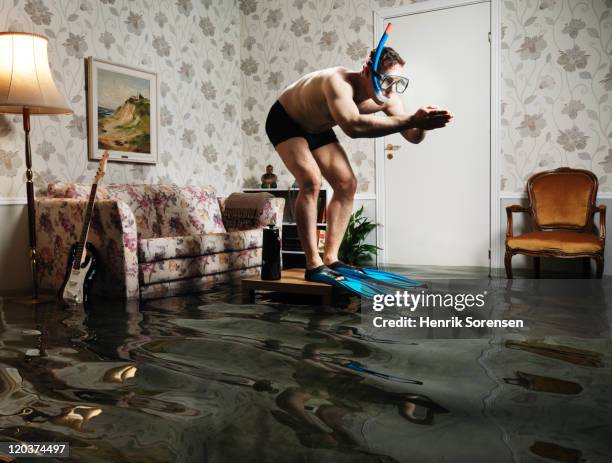 male swimmer in flooded living room - flooded room stock pictures, royalty-free photos & images