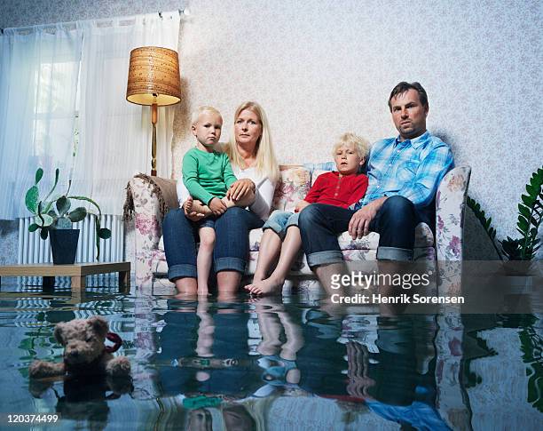family in sofa in flooded room - water damage stock-fotos und bilder