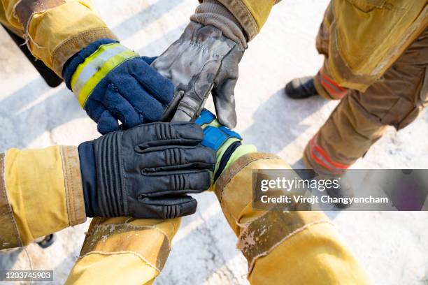 "we can, we will, we must. members of the fire department clash hands for strong group before firefighting - brand advocacy stock-fotos und bilder