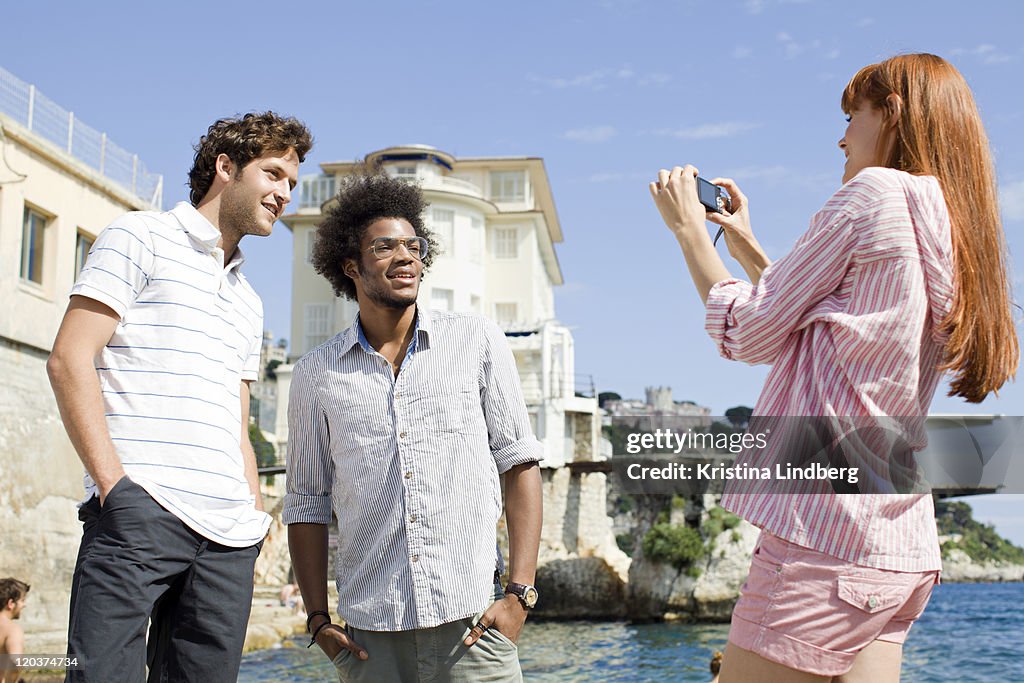 Woman taking picture of friends by the sea.