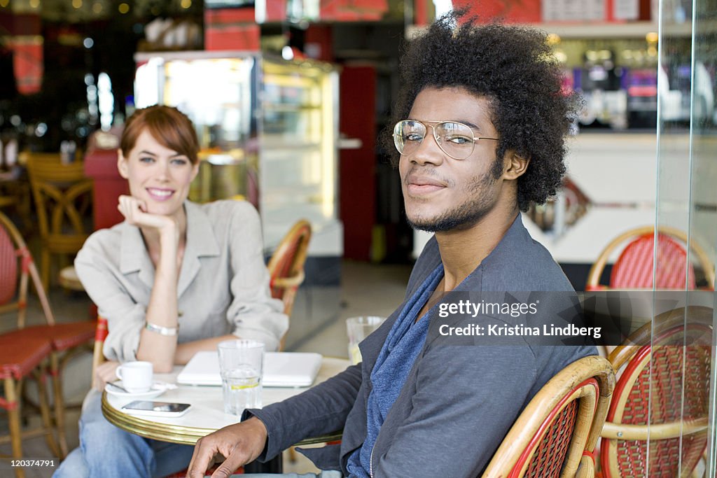 Man and woman in cafe smiling to the camera.
