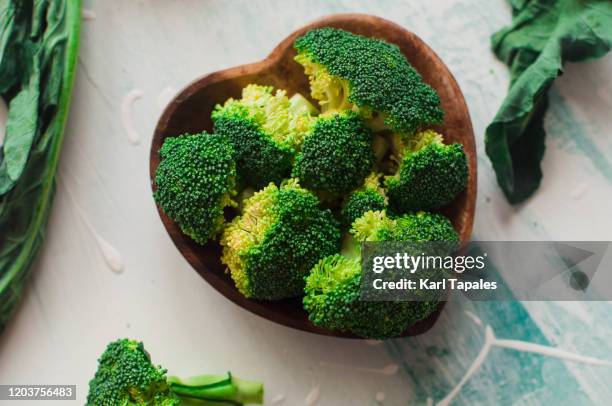 chopped broccoli on a wooden heart-shaped bowl - brécol fotografías e imágenes de stock