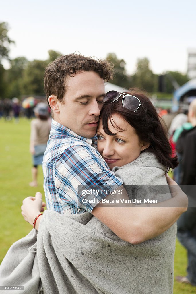 Man embracing girlfriend at festival,keeping warm.