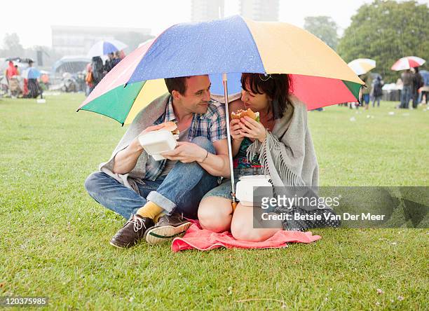 couple hiding under umbrella for rain at festival. - freshgrass festival photos et images de collection