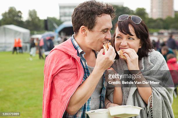 couple eating burgers at festival. - shawl stock pictures, royalty-free photos & images