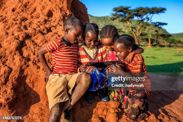 kleine afrikanische kinder mit digitalem tablet, ostafrika - african village stock-fotos und bilder