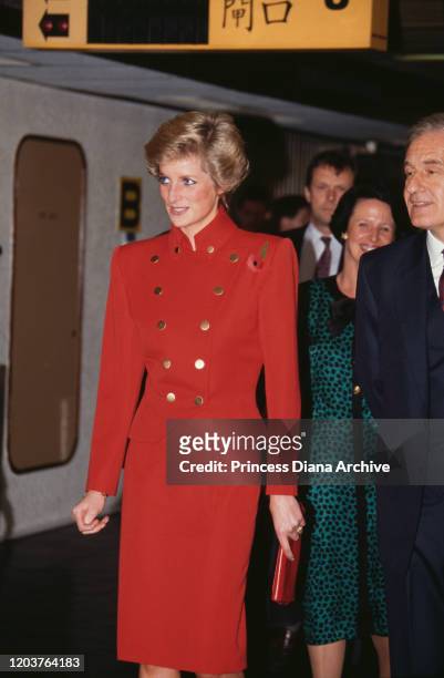 Diana, Princess of Wales leaves via the airport in Hong Kong, November 1989. She is wearing a red suit by Catherine Walker and a poppy.