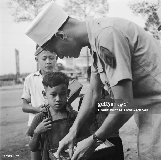 Soldier of the French Foreign Legion buys a packet of Chiclets chewing gum from a small boy in Vietnam, circa 1950.