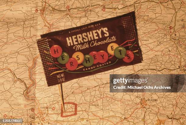 Packet of candy-coated Hershey's milk chocolate on a map of Pennsylvania, showing the location of the original Hershey chocolate factory in Hershey,...