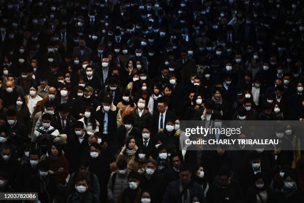 Mask-clad commuters make their way to work during morning rush hour at the Shinagawa train station in Tokyo on February 28, 2020. Tokyo's key Nikkei...