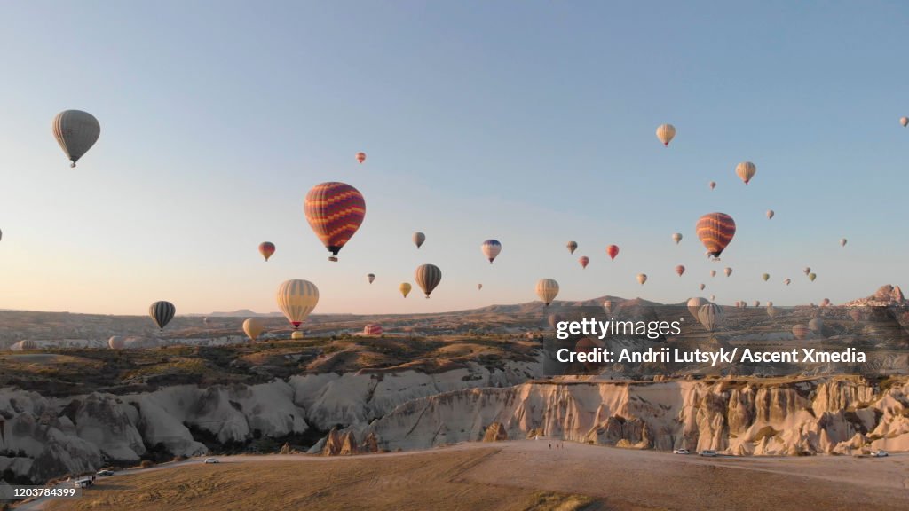 Hot air balloons rise above desert landscape