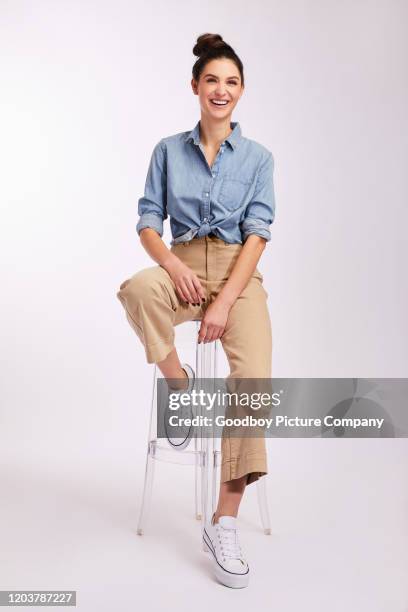 jeune femme riante de brunette s'asseyant au-delà d'un fond gris - tabouret photos et images de collection
