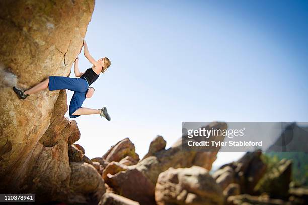young female rock climber bouldering. - boulder rock stock-fotos und bilder