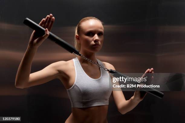 portrait of young woman exercising - nunchucks stock-fotos und bilder