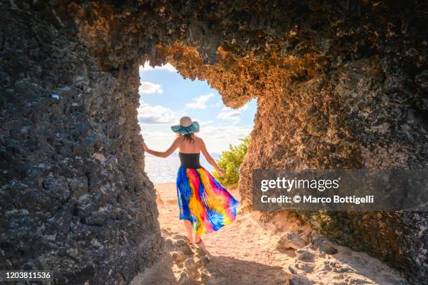 woman getting out of a cave overlooking the sea, yucatan peninsula, mexico - multi colored skirt stockfoto's en -beelden