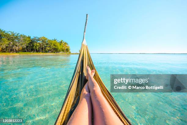 personal perspective of woman relaxing on hammock on water, mexico - karibische kultur stock-fotos und bilder