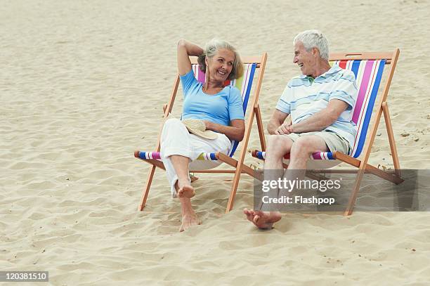 senior couple enjoying day out at the beach - man on the beach relaxing in deckchair fotografías e imágenes de stock