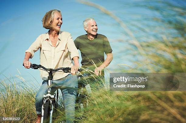 senior couple enjoying day out on their bicycles - ouderen stockfoto's en -beelden