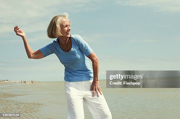 senior woman having fun at the beach - lanzar actividad física fotografías e imágenes de stock