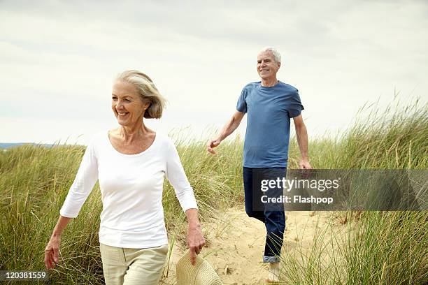 senior couple enjoying day out at the beach - senior women walking stock pictures, royalty-free photos & images