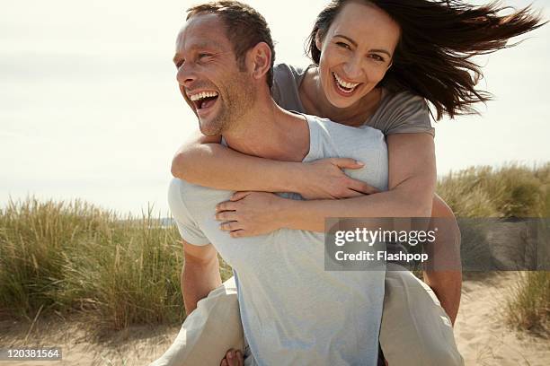 couple enjoying day out at the beach - pareja de mediana edad fotografías e imágenes de stock