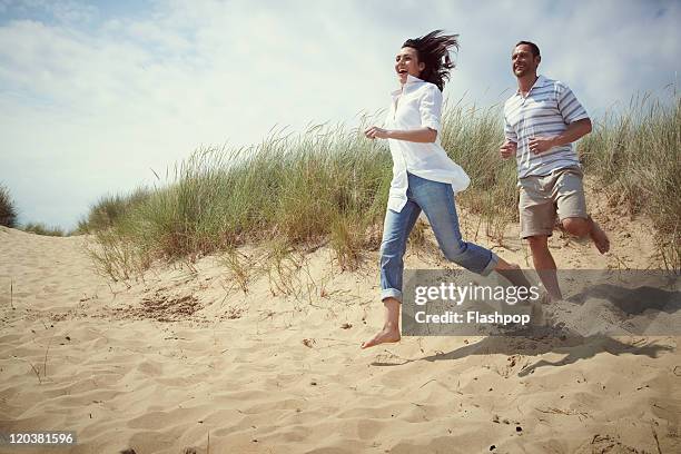 couple enjoying day out at the beach - couple running on beach stock pictures, royalty-free photos & images