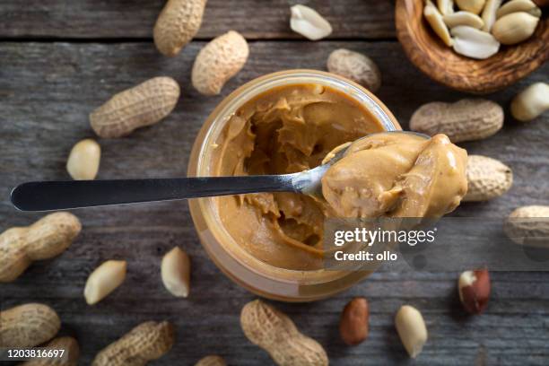 spoon and pot of peanut butter on wooden background - peanut butter stock pictures, royalty-free photos & images