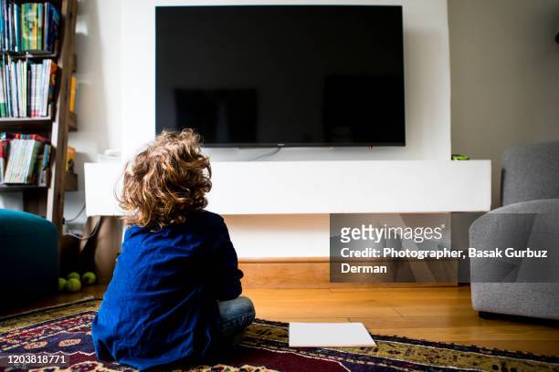 rear view of a kid sitting and watching television - kid watching tv stock-fotos und bilder