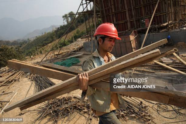 This picture taken on February 8, 2020 shows a Chinese worker carrying materials for the first rail line linking China to Laos, a key part of...