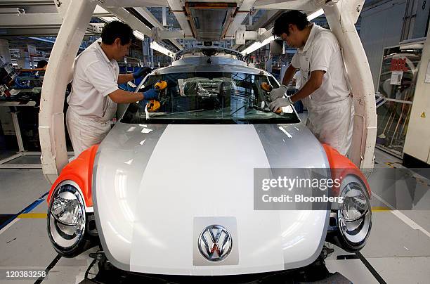 Employees place a windshield on the new generation Volkswagen AG Beetle at the company’s assembly plant in Puebla, Mexico, on Friday, Aug. 5, 2011....