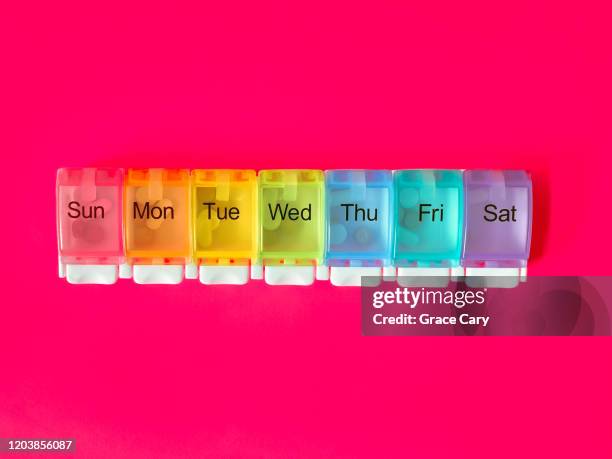 medication in multicolored pill organizer on pink background - prozac ストックフォトと画像