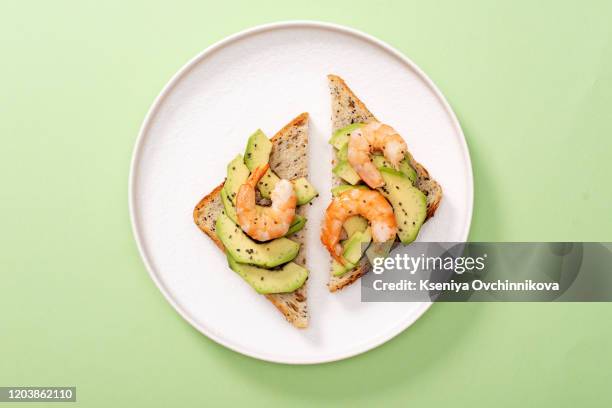 healthy delicious snack. toasts with avocado, shrimps and arugula on pastel green background. top view, flat lay. - stor räka bildbanksfoton och bilder