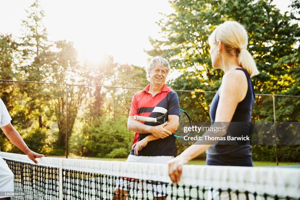 Smiling senior couple in discussion during early morning tennis match
