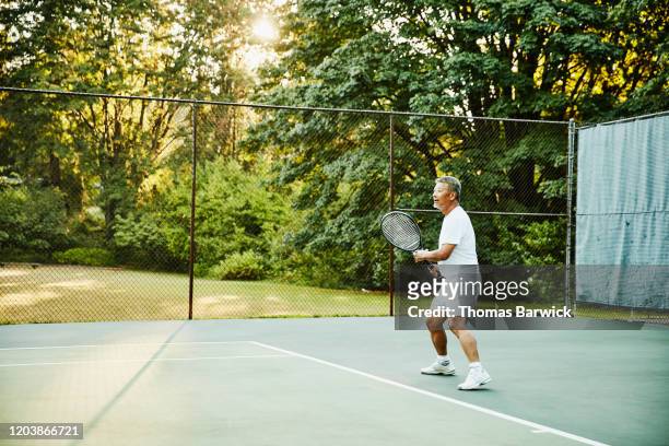 Senior man playing tennis during early morning match