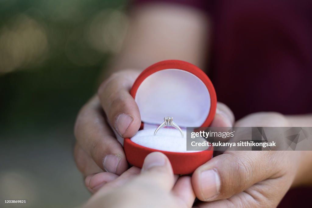 Young man presenting ring as a gift to girlfriend