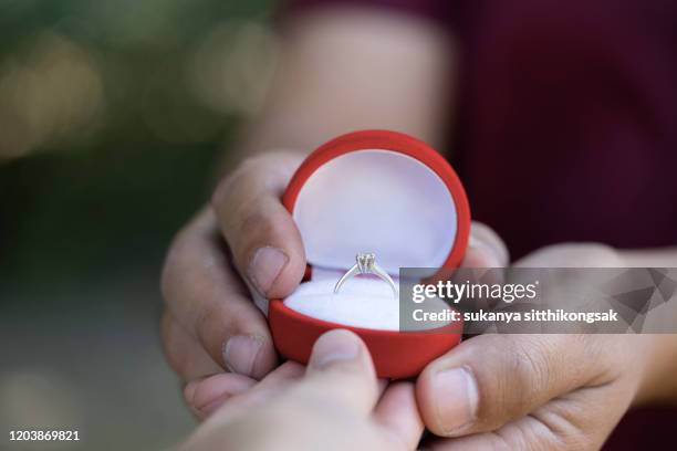 young man presenting ring as a gift to girlfriend - wedding gift stockfoto's en -beelden