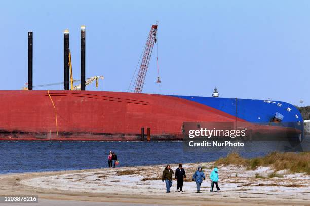 People walk the beach near the Golden Ray cargo ship on February 27, 2020 in Jekyll Island, Georgia. In about a month, a salvage company will begin...