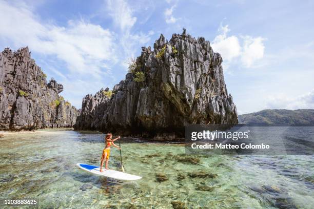asian woman stand up paddling, el nido, philippines - el nido stock pictures, royalty-free photos & images