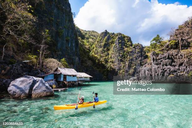 asian couple kayaking in a lagoon, coron, palawan, philippines - filipino stockfoto's en -beelden