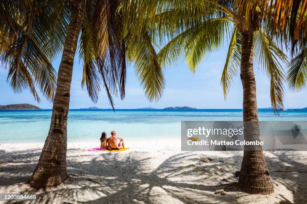 adult couple sitting at the beach, coron, philippines - philippines beach stock pictures, royalty-free photos & images