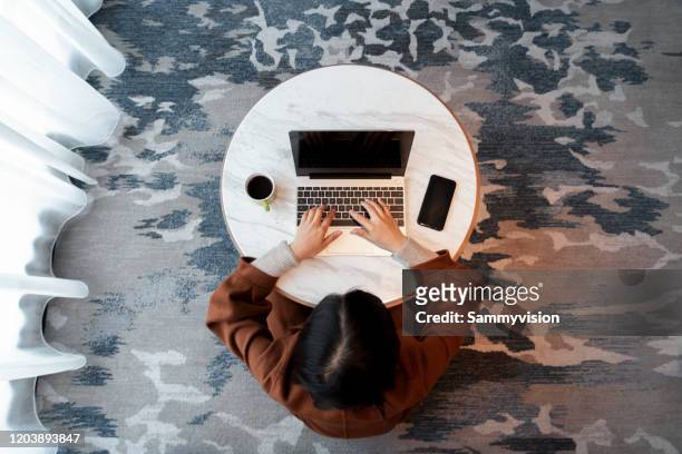 directly above view of a woman working on laptop in bedroom - hands circle fotografías e imágenes de stock
