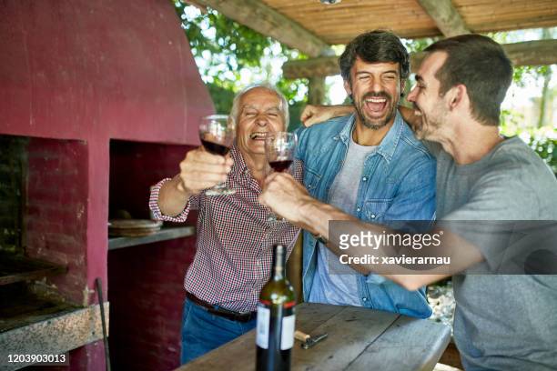 laughing argentine men toasting with red wine - argentina wine stock pictures, royalty-free photos & images