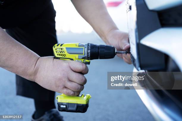 using wireless power drill to car plate installation - broca imagens e fotografias de stock