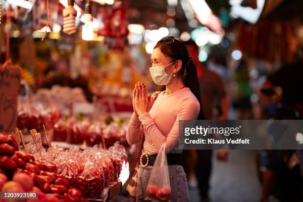 Woman with pollution mask greeting at market stall