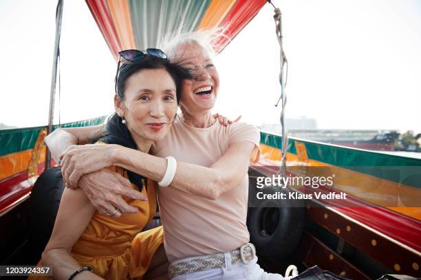portrait of woman sitting with friend in boat - elderly asian foto e immagini stock