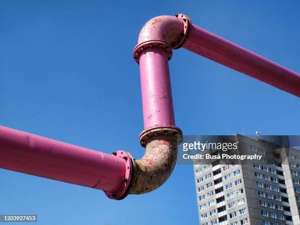 giant pink water pipes with housing tower in the background in berlin, germany - plattenbau stock-fotos und bilder
